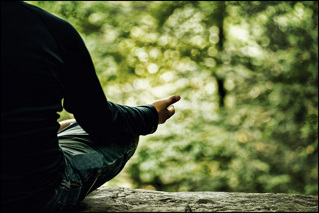 man practiciing meditation in a park 