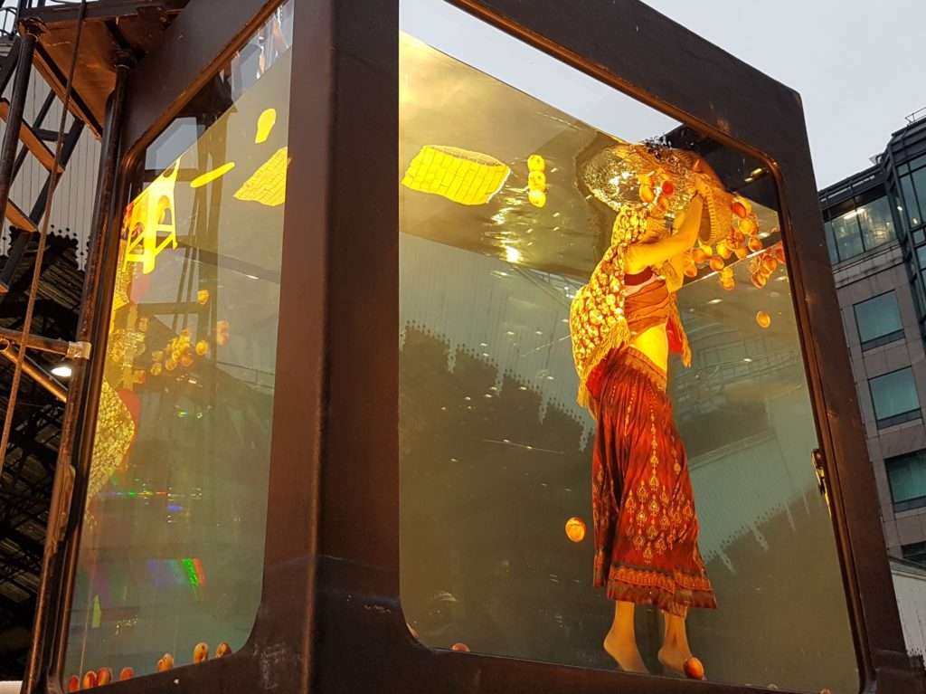 lady suspended in a glass tank catching fruit - Holoscenes, Great Fire of London commemorations 