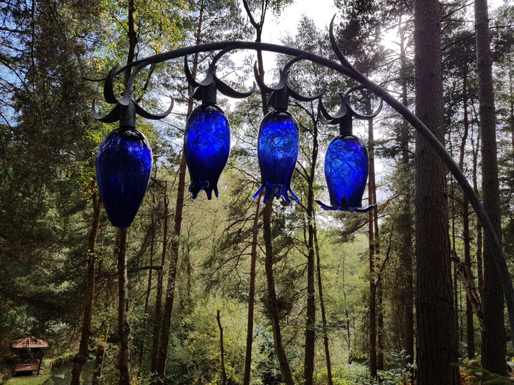 close up of blue glass tulips suspended in woodlands at the Churt Sculpture Park near Farnham 