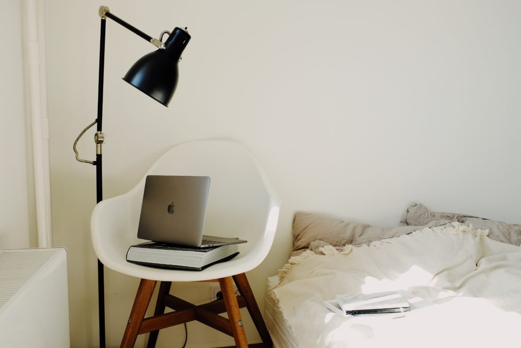 portable laptop on chair beside bed for remote working