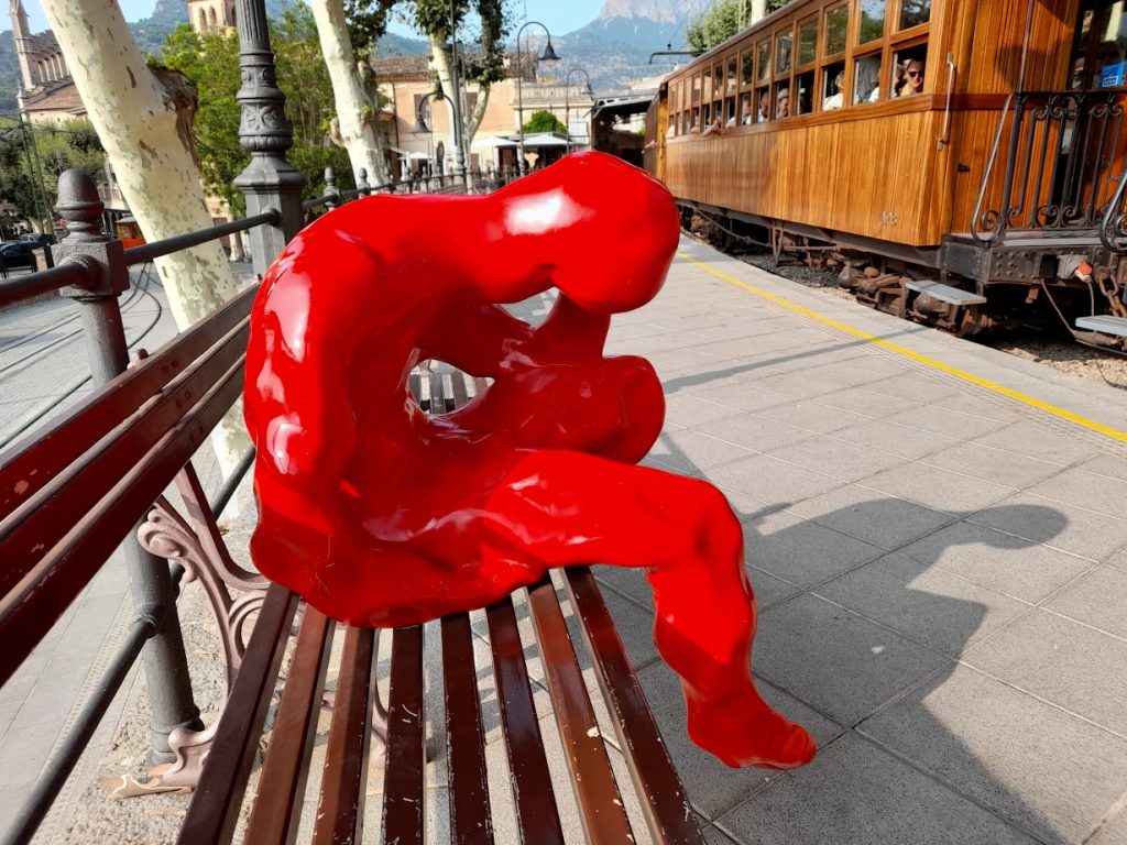 Statue of man holding his head in despair on a bench at Soller train station in Mallorca